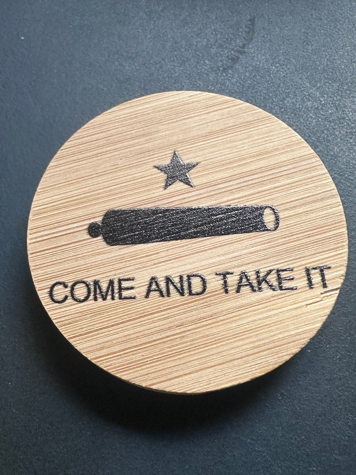 Come and Take It cannon and star engraved in black on a bamboo bottle opener