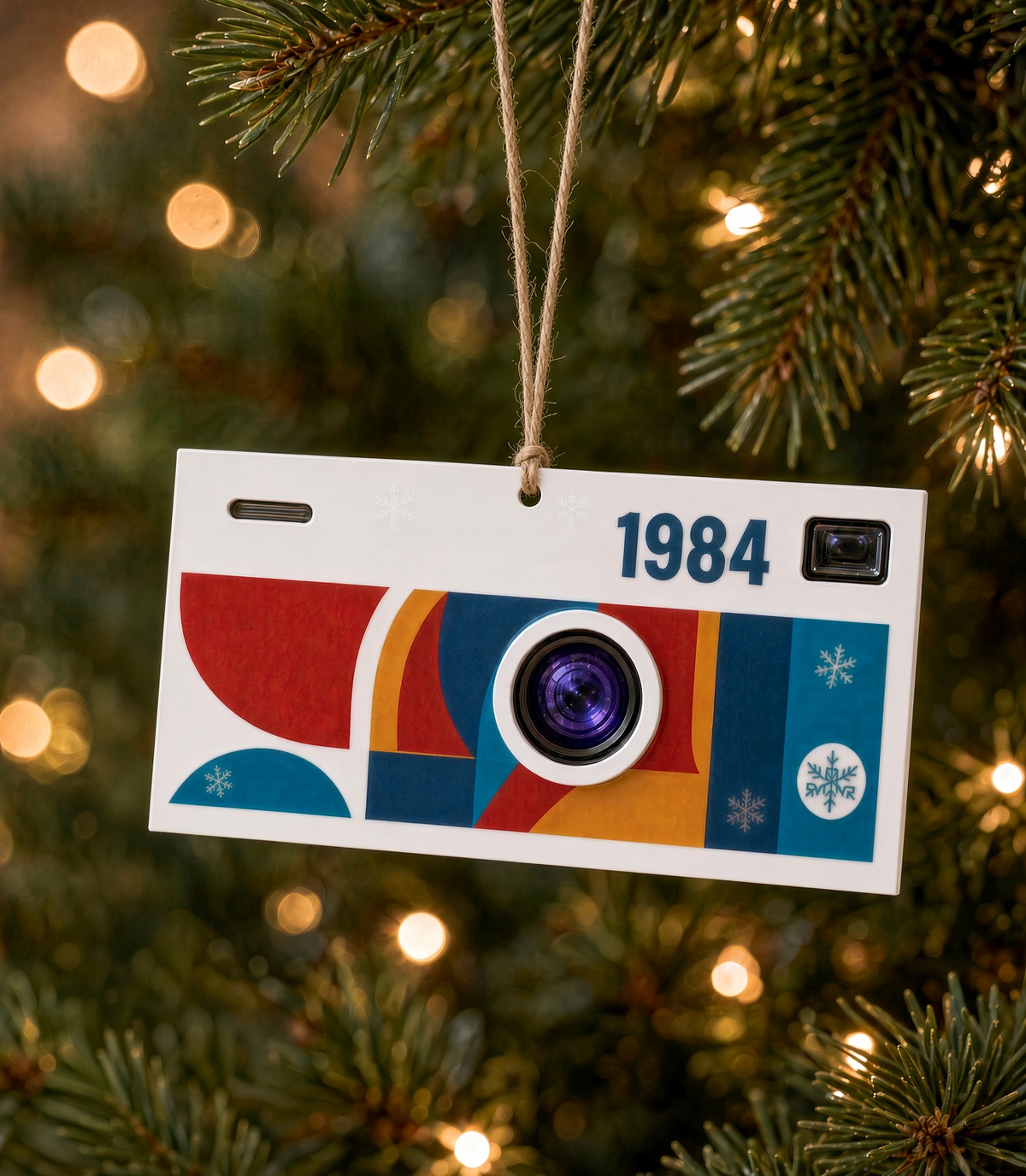 Retro camera Christmas ornament in white acrylic with colorful UV print and 1984 on top, hanging on a Christmas tree
